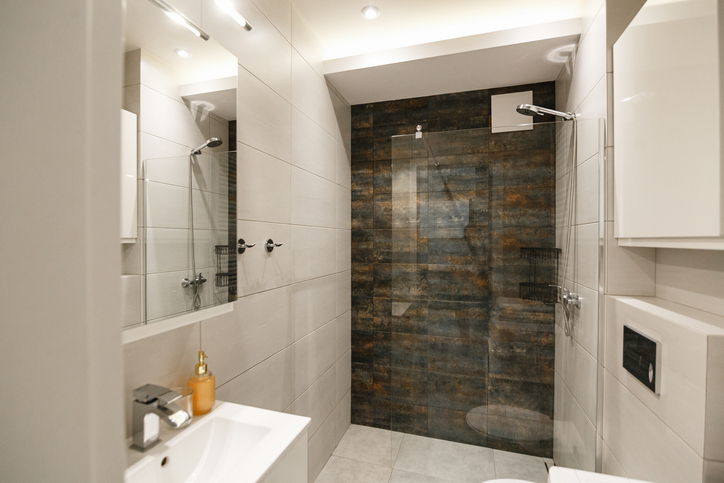 Modern minimalist bathroom interior with light tiles and dark textured stone shower wall. Luxury restroom architecture, contemporary home renovation, sleek walk-in shower design, minimalist apartment